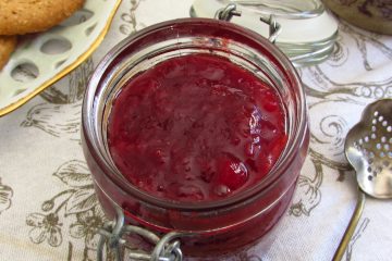 Strawberry jam in a glass jar with crackers
