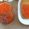 Carrot jam on glass jar with crackers