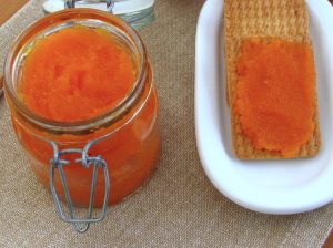 Carrot jam on glass jar with crackers