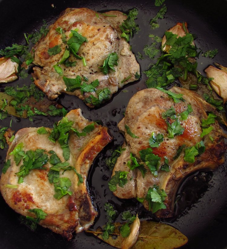 Fried pork chops with coriander on a frying pan
