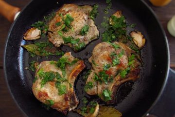 Fried pork chops with coriander on a frying pan