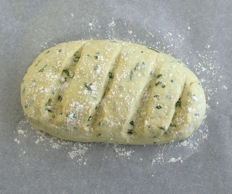 Coriander and garlic bread dough sprinkled with flour on a baking tray