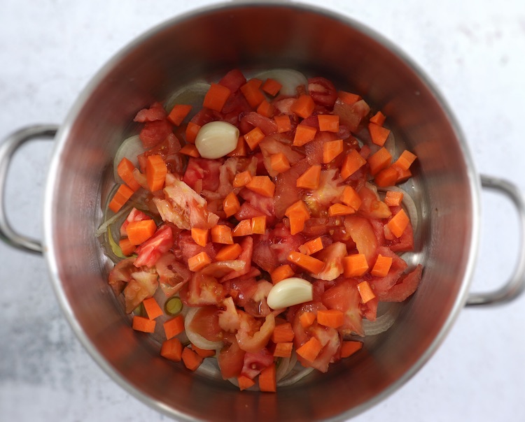 Azeite, cebola, tomate e alhos descascados num tacho