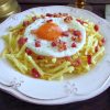 Fried egg with fries and small pieces of bacon on a plate