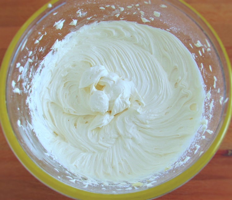 Mistura de manteiga, leite, essência de baunilha e açúcar em pó numa taça de vidro