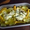 Baked ling fish with orange and lemon on a baking dish