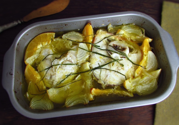 Ling fish in the oven with orange and lemon on a baking dish