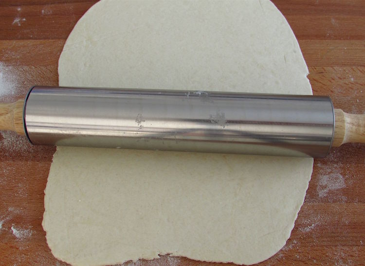 Puff pastry with a rolling pin on a table sprinkled with flour