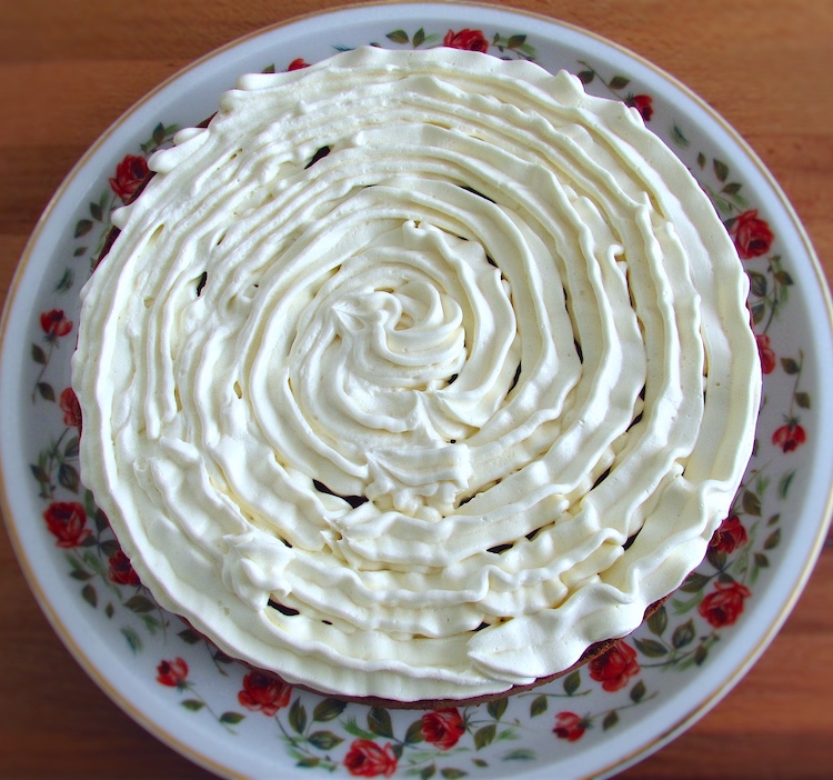 Metade de bolo de chocolate recheado com creme de manteiga num prato