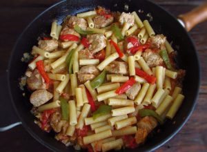 Pasta with pork and peppers on a frying pan