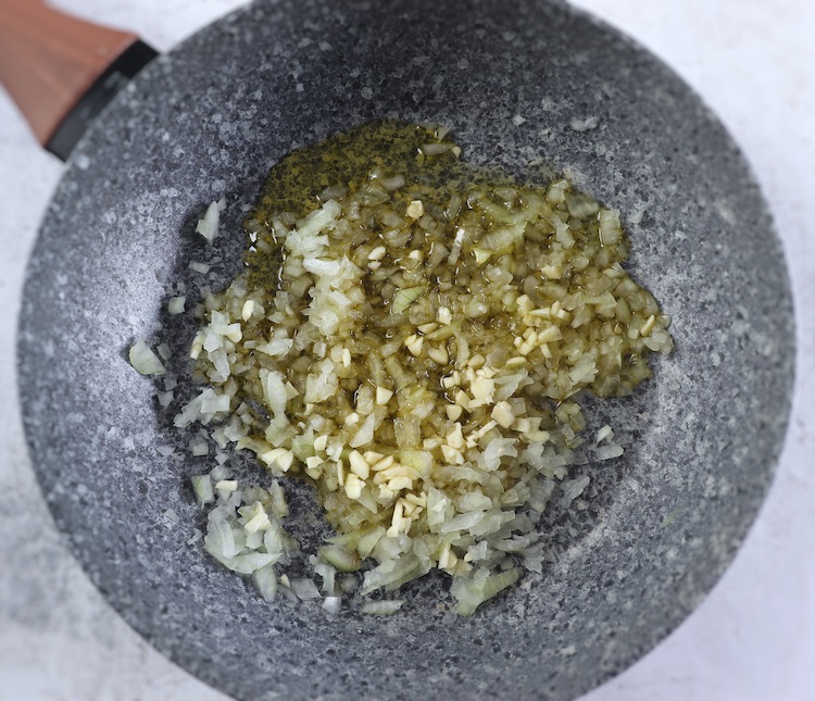 Chopped onion, chopped garlic and olive oil on a frying pan