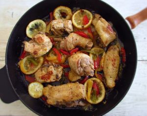 Fried chicken with peppers and lemon on a frying pan