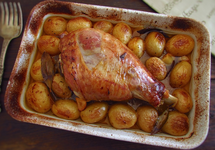 Roasted turkey leg with potatoes on a baking dish