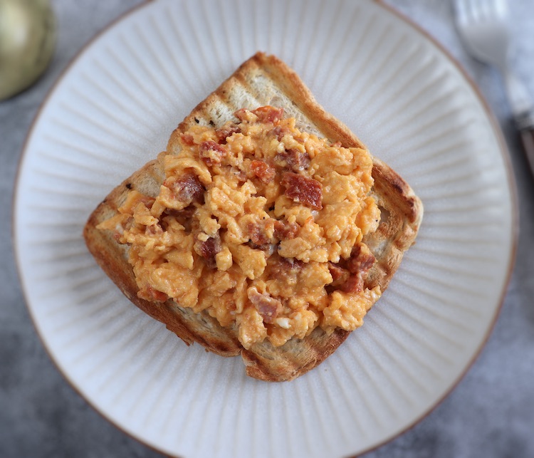 Scrambled eggs with chouriço and a toasted bread slice on a plate