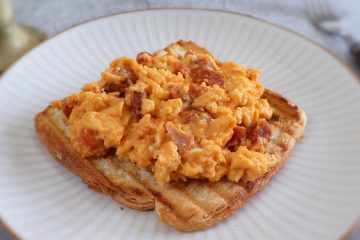 Scrambled eggs with chouriço and a toasted bread slice on a plate