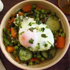 Ervilhas com cenoura, curgete e ovos escalfados num prato