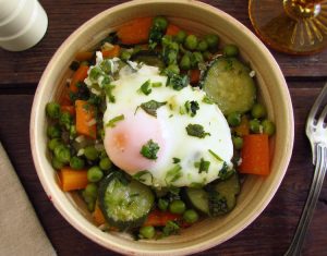 Peas with carrot, courgette and poached eggs on a dish