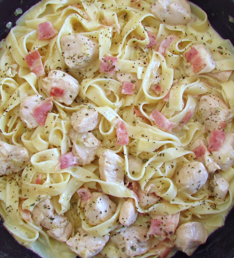 Fried chicken breast with bacon and tagliatelle on a frying pan