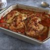 Baked chicken legs with tomato and oregano on a baking dish
