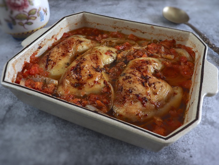 Coxas de frango no forno com tomate e orégãos numa assadeira