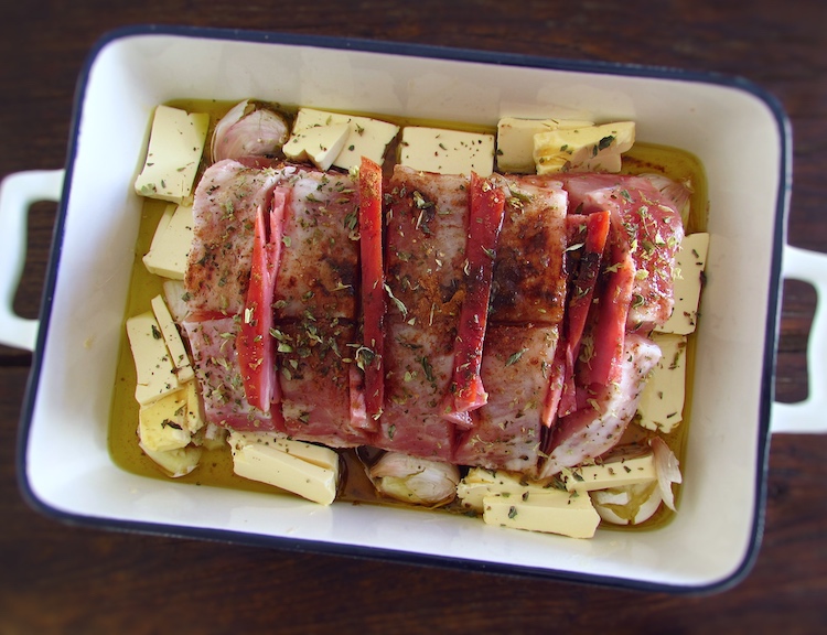 Pork loin seasoned with salt, honey, pepper, cinnamon, oregano, unpeeled crushed garlic, Worcestershire sauce, olive oil and margarine cut into small pieces on a baking dish