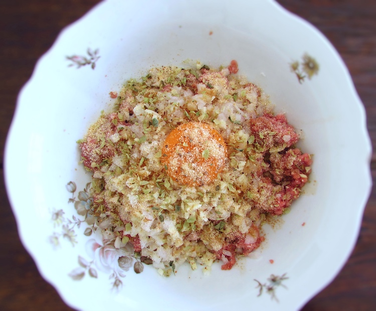 Minced meat seasoned with a little salt, a chopped onion, nutmeg, pepper, oregano, Worcestershire sauce, chopped garlic, breadcrumbs and egg yolk in a bowl
