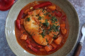 Peixe guisado com cenoura e pimento vermelho num prato fundo