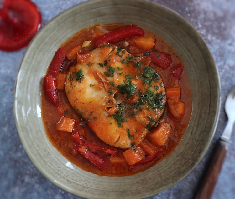 Peixe guisado com cenoura e pimento vermelho num prato fundo