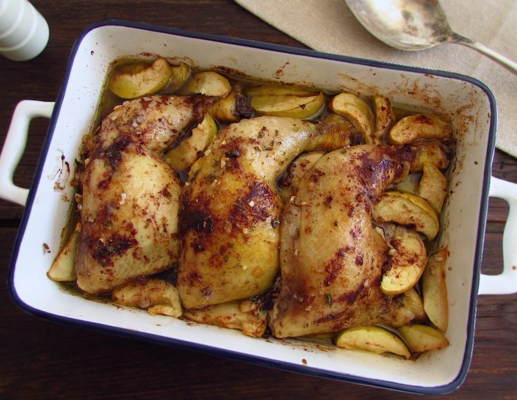 Chicken legs in the oven with apple on a baking dish