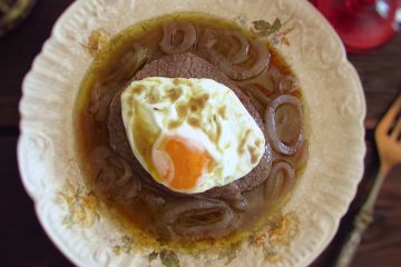 Stewed beef medallions with fried egg on a plate
