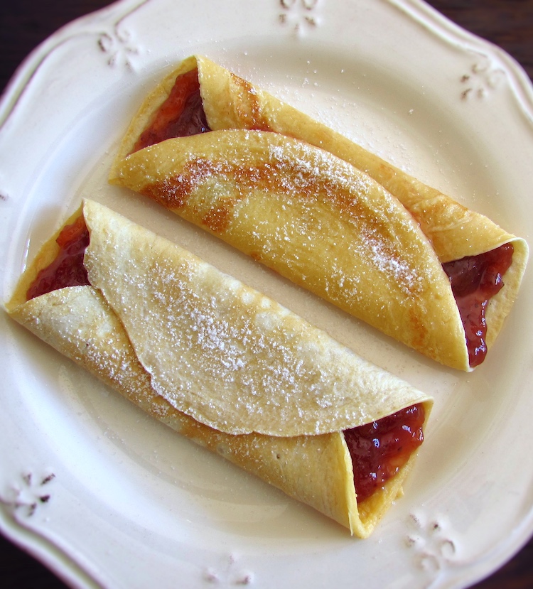 Crepes filled with strawberry jam on a plate