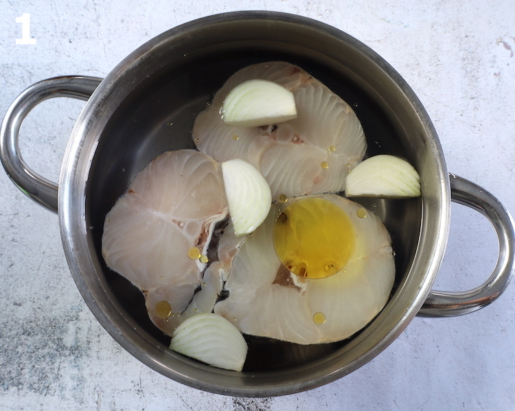 Postas de pescada num tacho com água temperada com sal, um fio de azeite e cebola cortada em pedaços