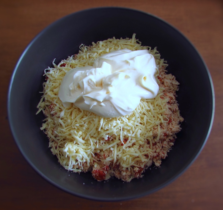 Chopped chicken, chouriço cut into pieces, peeled garlic and nutmeg with mayonnaise and grated cheese in a bowl