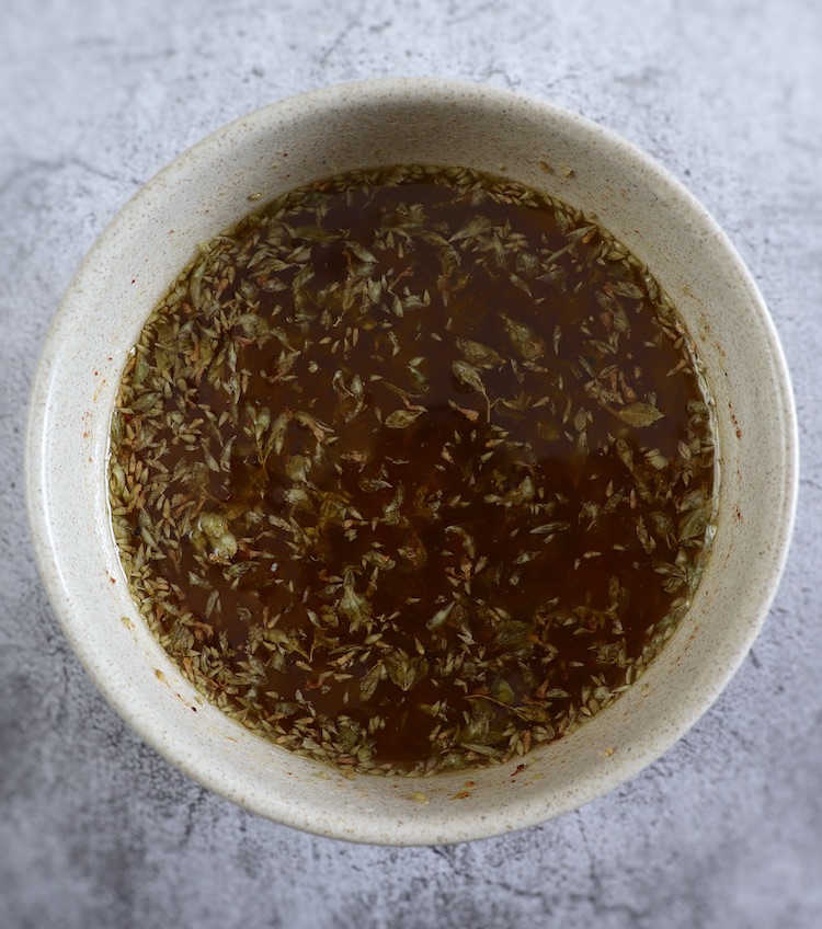 Sauce of mustard, olive oil, salt, lemon juice, oregano, grated garlic and nutmeg in a bowl