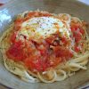 Esparguete com ovos escalfados em molho tomate num prato fundo