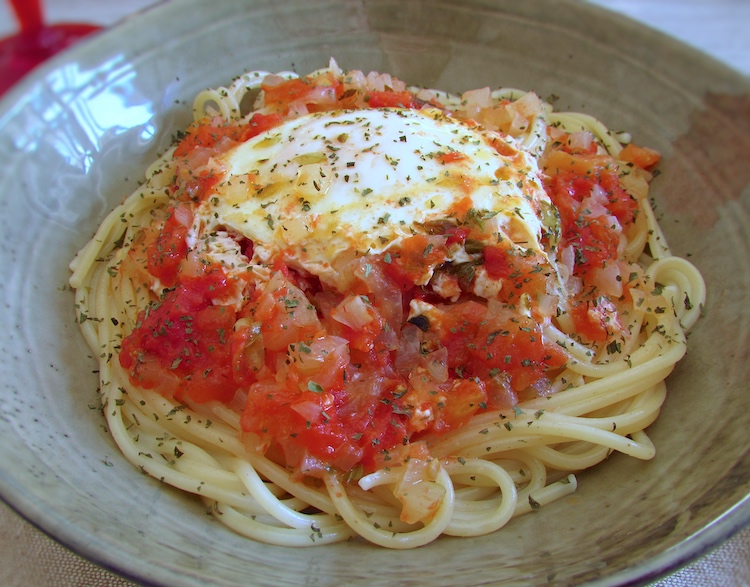 Esparguete com ovos escalfados em molho tomate num prato fundo