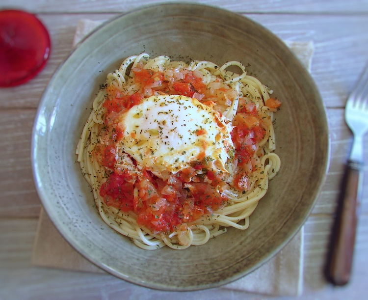 Spaghetti with poached eggs in tomato sauce on a dish bowl
