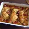 Roasted chicken legs with chouriço and garlic on a baking dish