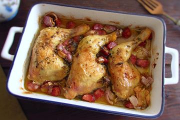 Roasted chicken legs with chouriço and garlic on a baking dish