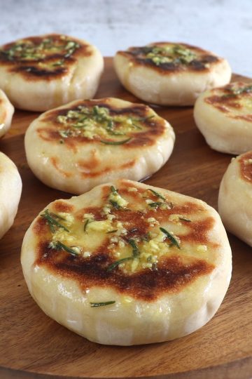 Pão pita caseiro com molho de azeite numa tábua de madeira redonda