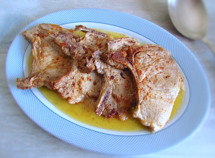 Fried pork chops on a platter with a spoon