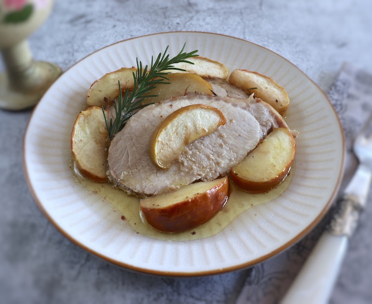Slices of baked pork loin with apple and rosemary on a plate