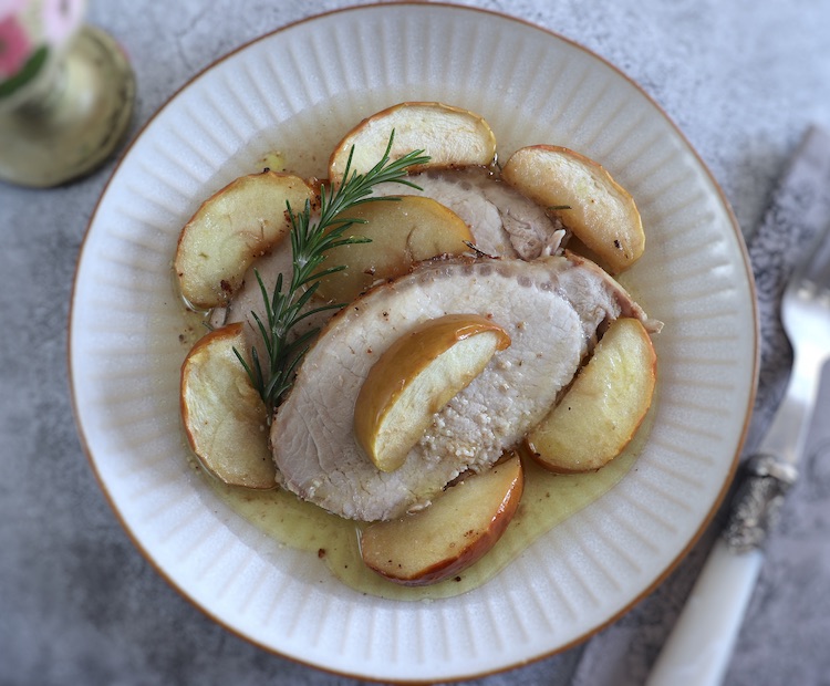 Slices of baked pork loin with apple and rosemary on a plate
