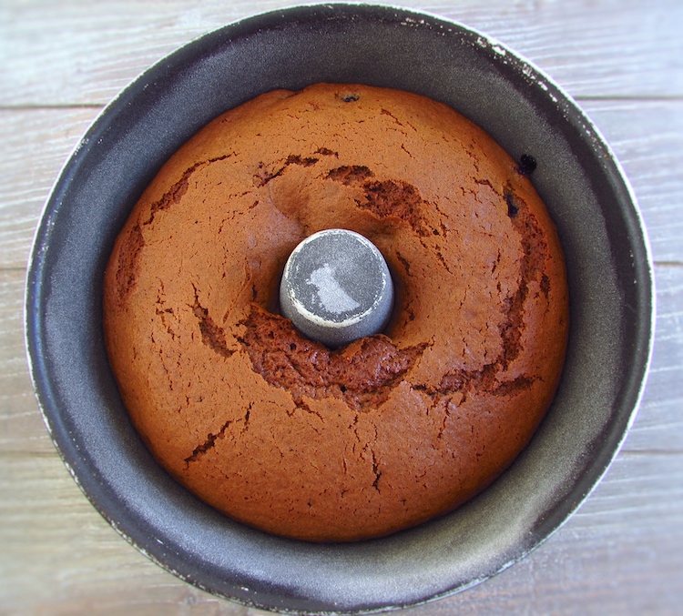 Bolo de açúcar mascavado com frutos vermelhos numa forma de bolos redonda com furo no meio