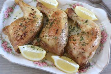 Baked chicken legs with garlic and lemon on a platter