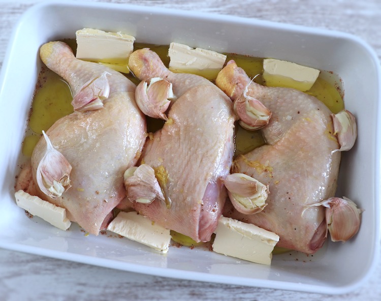 Cuisses de poulet assaisonnées d'ail et de citron sur un plat allant au four