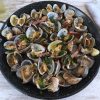 Clams with bacon and garlic on a frying pan