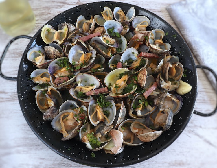 Clams with bacon and garlic on a frying pan