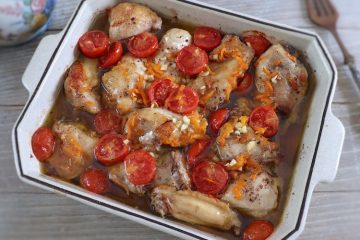 Chicken in the oven with cherry tomato and carrot on a baking dish