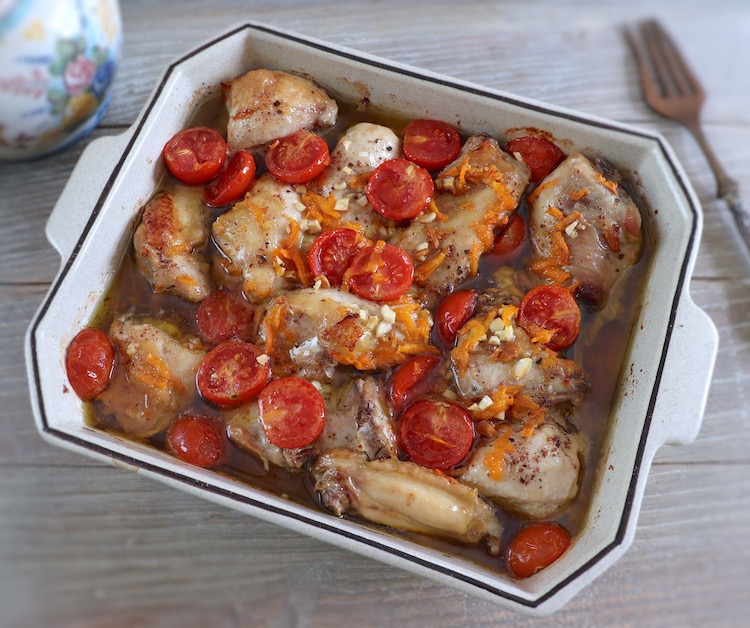 Baked chicken with cherry tomato and carrot on a baking dish